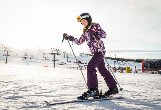 Winsport Youth ski teen girl on skis traversing flat snow