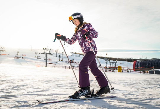 Winsport Youth ski teen girl on skis traversing flat snow