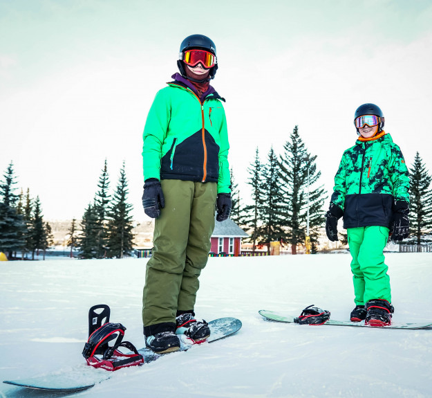 Winsport Snowboard teen boys wearing green snow suits posing with snowboards