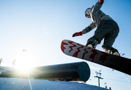 SBBasicsnowboarder doing a 180 while exiting a rail at winsport snowboard