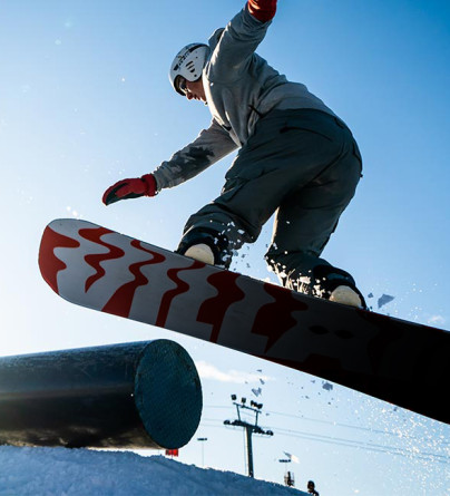 SBBasicsnowboarder doing a 180 while exiting a rail at winsport snowboard