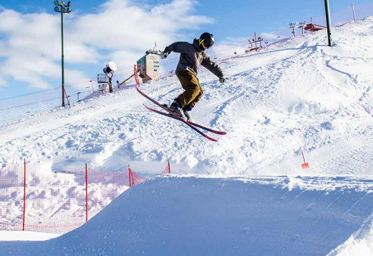 skiier casually spinning off a slopestyle jump at winsport