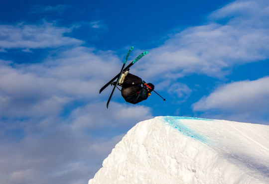 skiier doing a backflip off a slopestyle jump at winsport v2