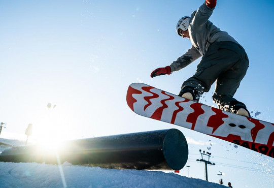 snowboarder doing a 180 while exiting a rail at winsport