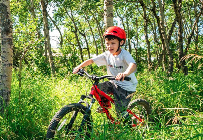 Young kid riding his bike through a trail in the trees at winsport