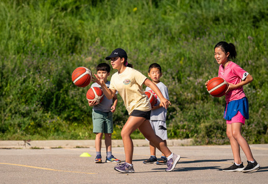 Group of campers playing basketball on asphalt court