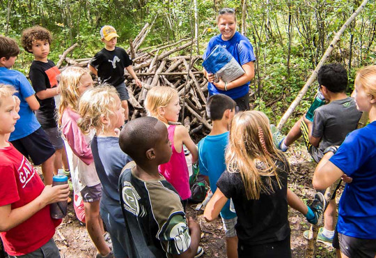 Group of children learning survival techniques from instructor at WinSport summer camp