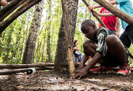 Group of young children learning how to build shelter in the wilderness at a WinSport summer camp v2