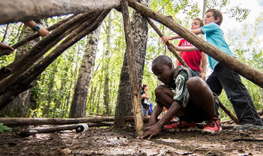 Group of young children learning how to build shelter in the wilderness at a WinSport summer camp