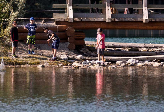 Summer campers stopping at a bridge to skip rocks over a shallow river v2