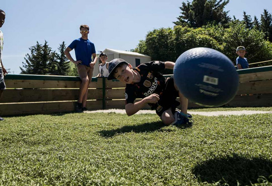 Children playing a game of gaga ball on a sunny day during summer camp at winsport