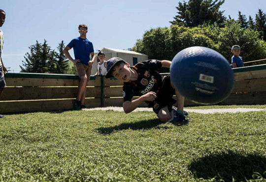 Children playing a game of gaga ball on a sunny day during summer camp at winsport