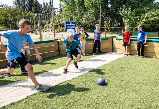 Group of summer campers playing gaga ball at a WinSport summer camp on a sunny day