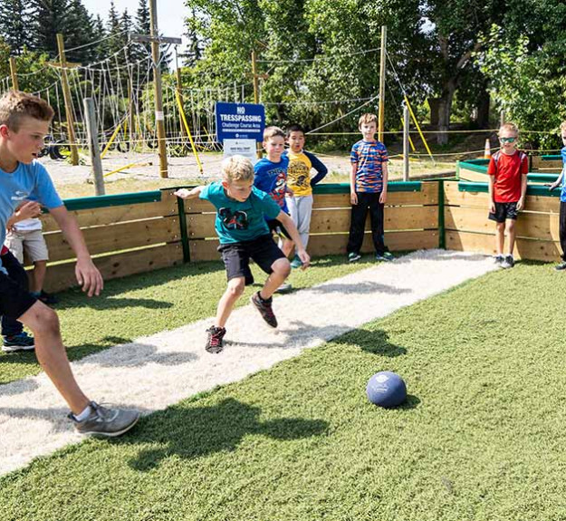 Group of summer campers playing gaga ball at a WinSport summer camp on a sunny day