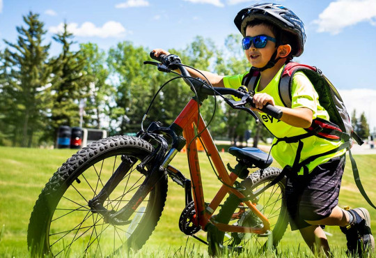 boy pushing his bike up a subtle hil learning how to bike